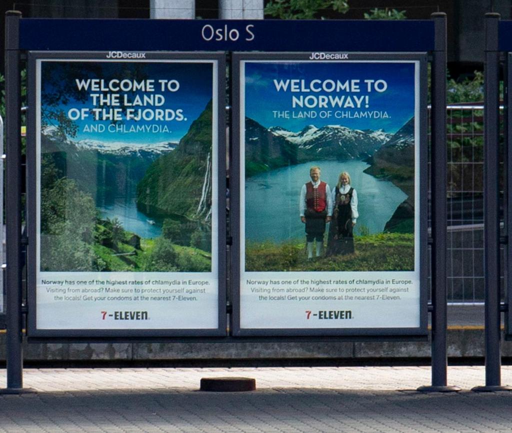 Reklameplakatar på Oslo S for 7-Eleven med overskriftene "Welcome to the Land of the Fjords. And Chlamydia." og "Welcome to Norway! The Land of Chlamydia.". Brødteksten på begge plakatar er: "Norway has one of the highest rates of chlamydia in Europe. Visiting from abroad? Make sure to protect yourself from the locals. Get your condoms at the nearest 7-Eleven." Foto.
