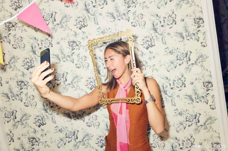 Ung kvinne tar selfie med en smarttelefon. Foto.