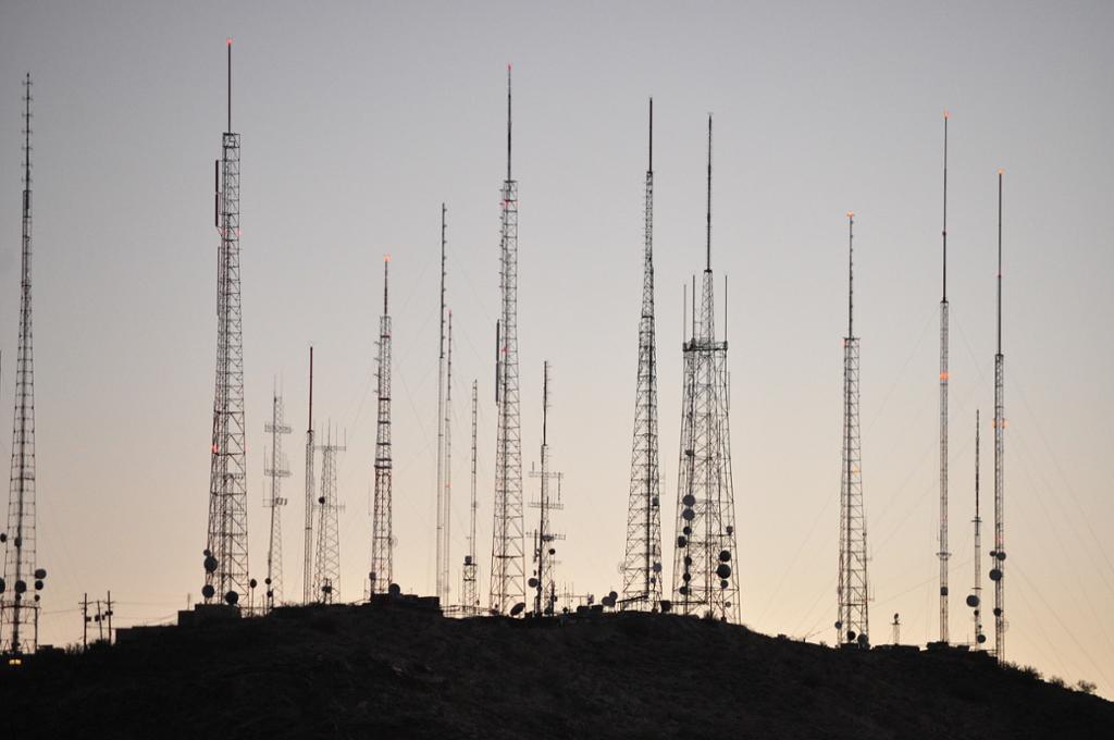 Flere høye radiomaster på en bakketopp i horisonten. Foto.