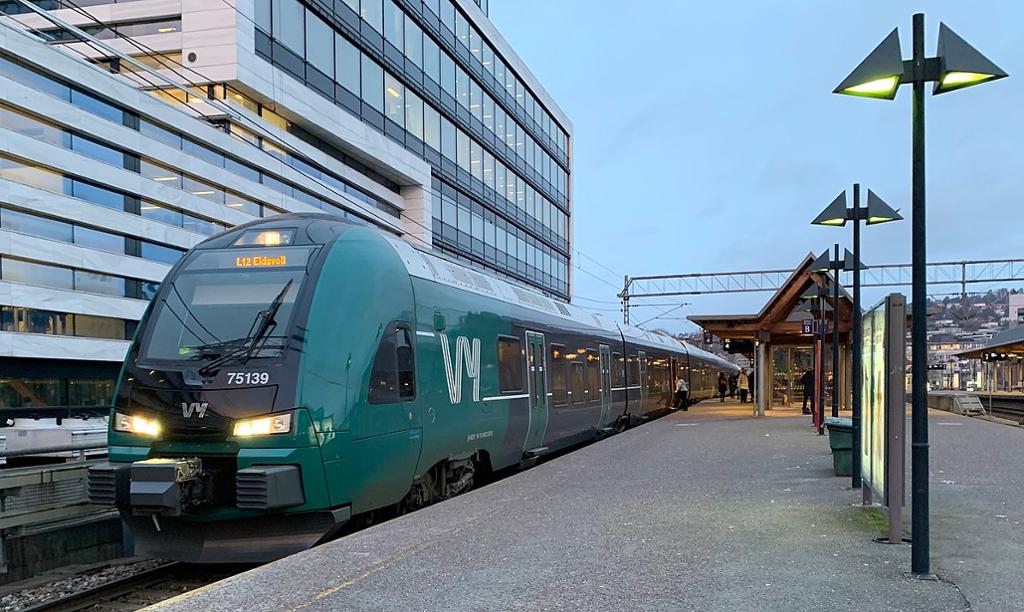 Eit grønt VY-tog som skal til Eidsvoll, står på perrongen. Foto. 