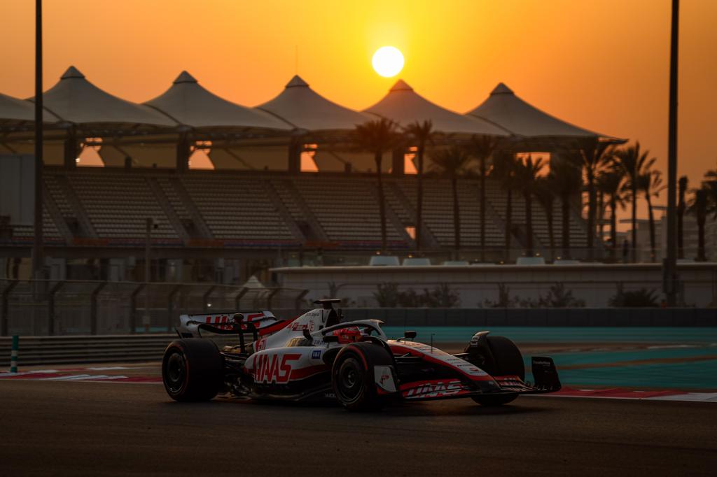 Formel 1-bil kjøres på en bane i solnedgang med en form for telt i bakgrunnen over tribunene og palmer. Foto. 