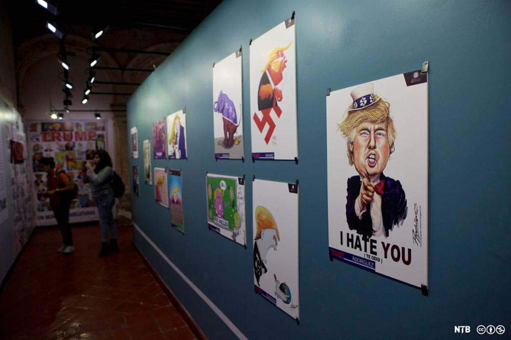 To studentar besøkjer utstillinga "Trump: A wall of caricatures", som viser fleire karikerte framstillingar av Donald Trump. Foto. 
