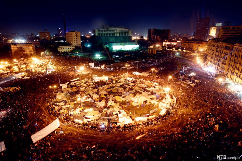 Oversiktsbilete over Tahrir-plassen om kvelden. Demonstrantar er samla. Ein sirkel av gatelys lyser opp. Foto.