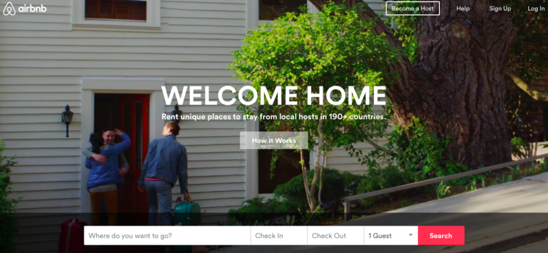 Hjemmesiden til Airbnb, med teksten «Welcome Home» og søkefelt for bestilling. Bakgrunnsbildet viser et hus med to personer som klemmer på utsiden, og en person med koffert. Skjermbilde.