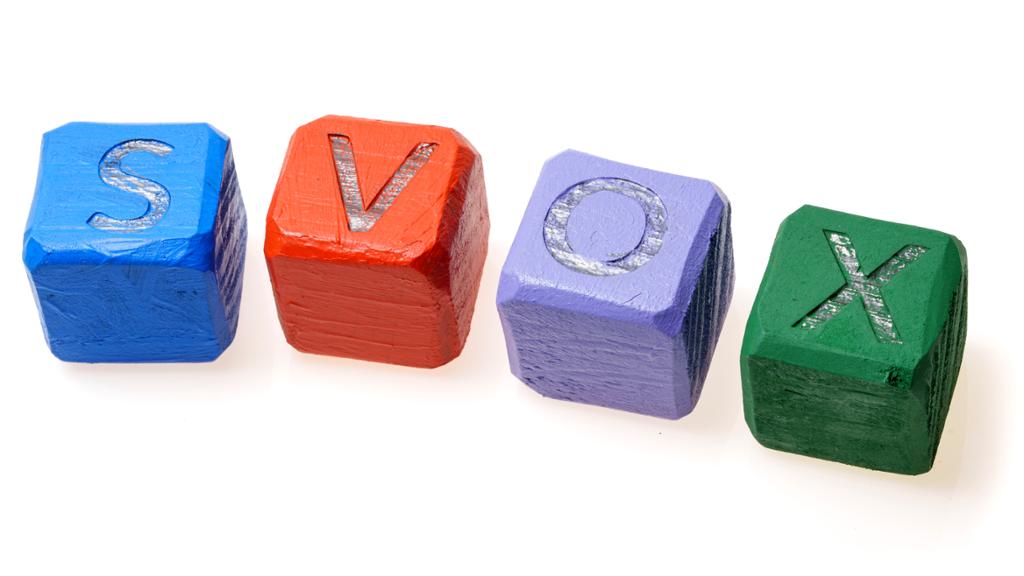 Fire klossar med bokstavane S, V, O og X på. Klossane har forskjellige fargar. Foto.