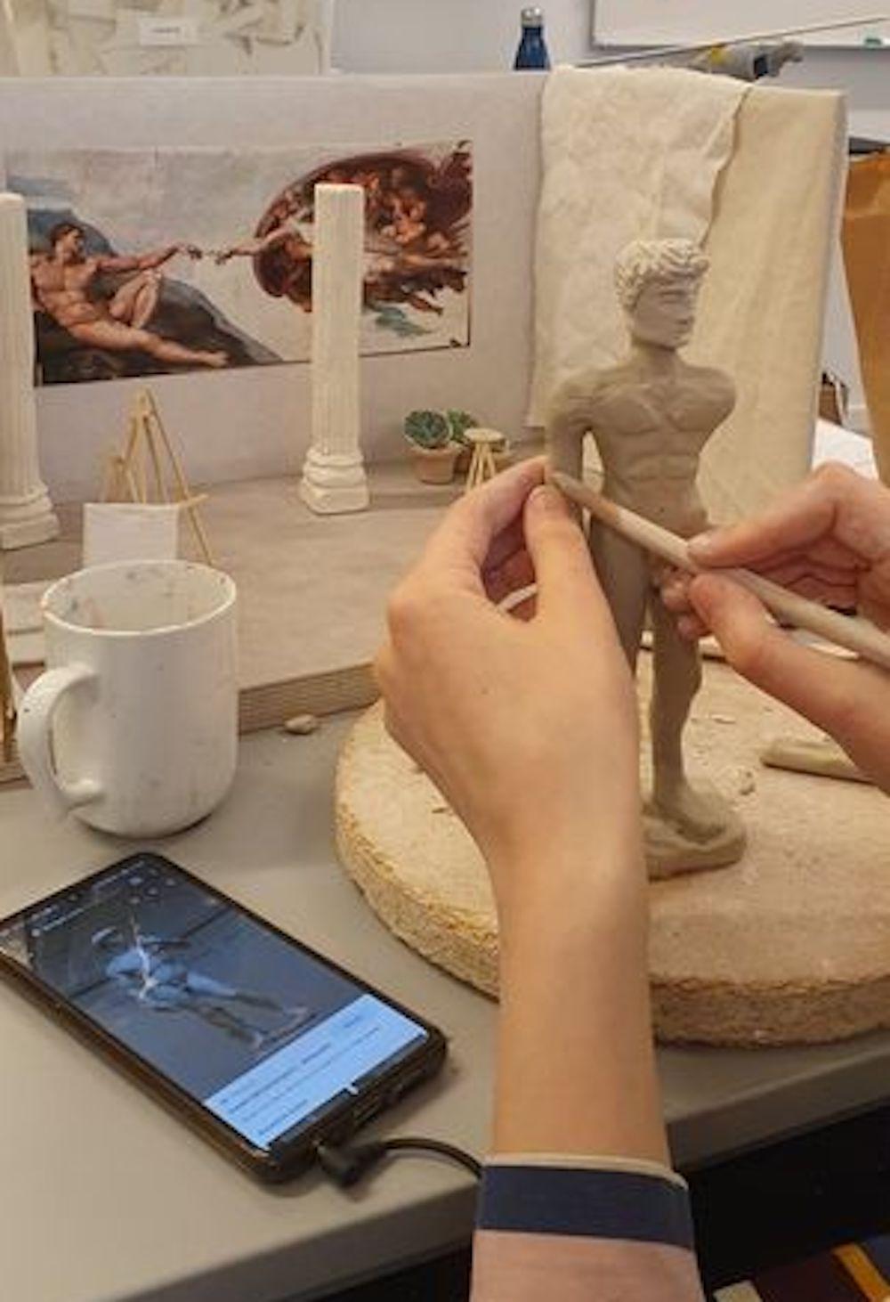 Hender modellerer skulpturen "David" av Michelangelo i leire. Foto. 