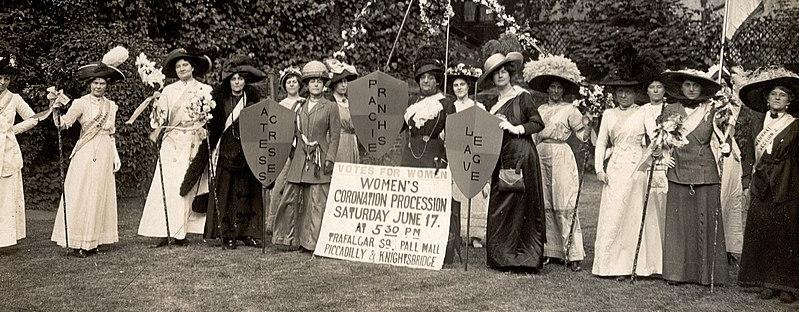 A photo taken at the end of the nineteenth century showing 16 middle/upper-class women dresses in the traditional dresses of the time. They are demonstrating for women's right to vote. 