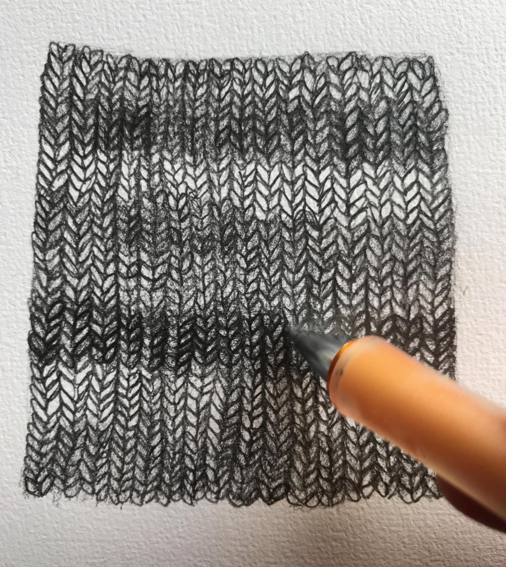 En stripet, strikket lapp er tegnet i ulike gråtoner. Foto.