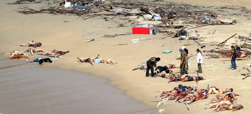 Innsatspersonell på ei strand full av døde menneske og gjenstandar etter tsunamien i 2004. Foto.