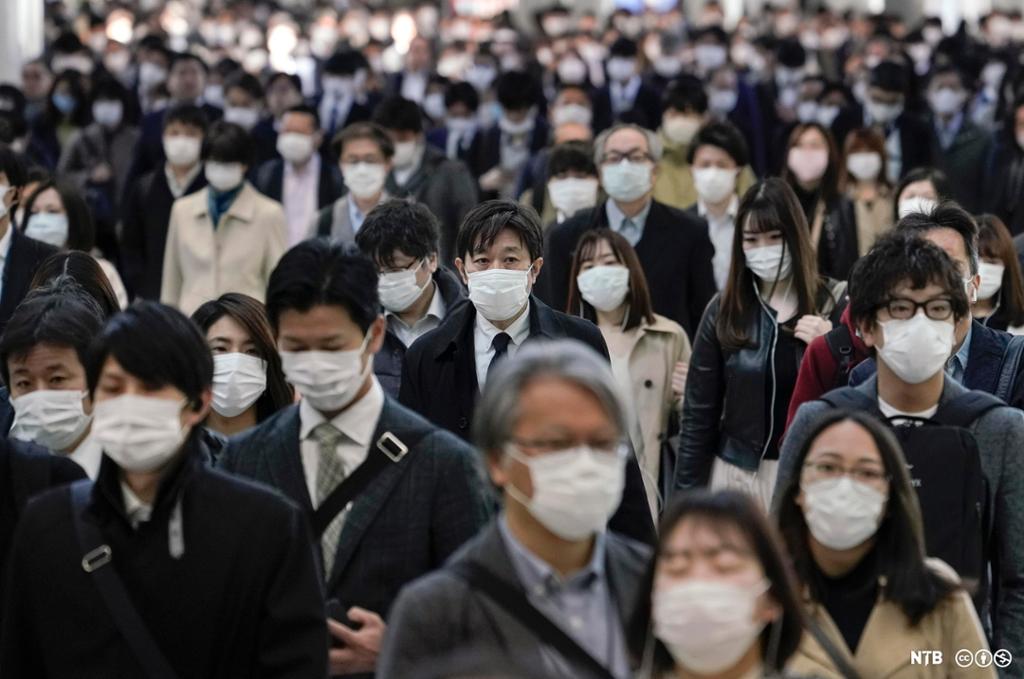 En stor mengde japanere på vei til jobb. Alle er pent kledd og har munnbind på. Foto. 
