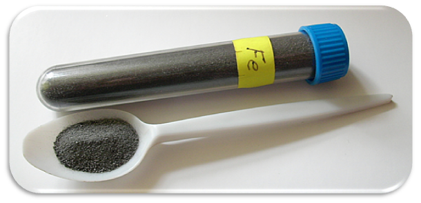 Eit reagensrør og ei plastskei med grått pulver. Reagensrøret er merket med Fe for jern. Foto.