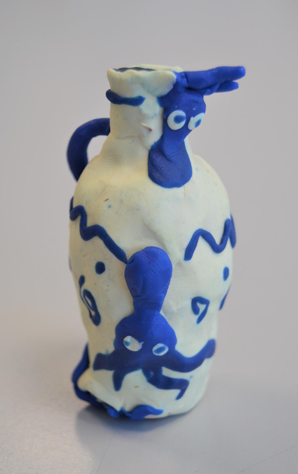 Kvit vase med blå blekksprutar i plastelina. Foto.