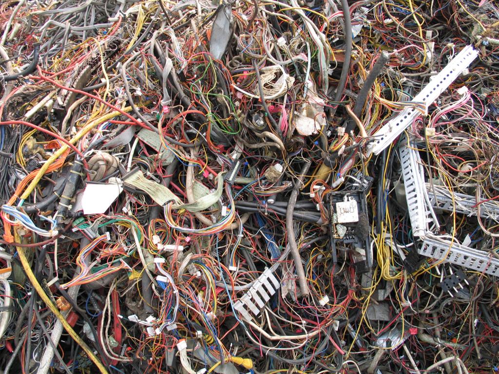 En haug med elektronisk avfall. Mange ledninger og noen metallbiter i ulike farger. Foto.