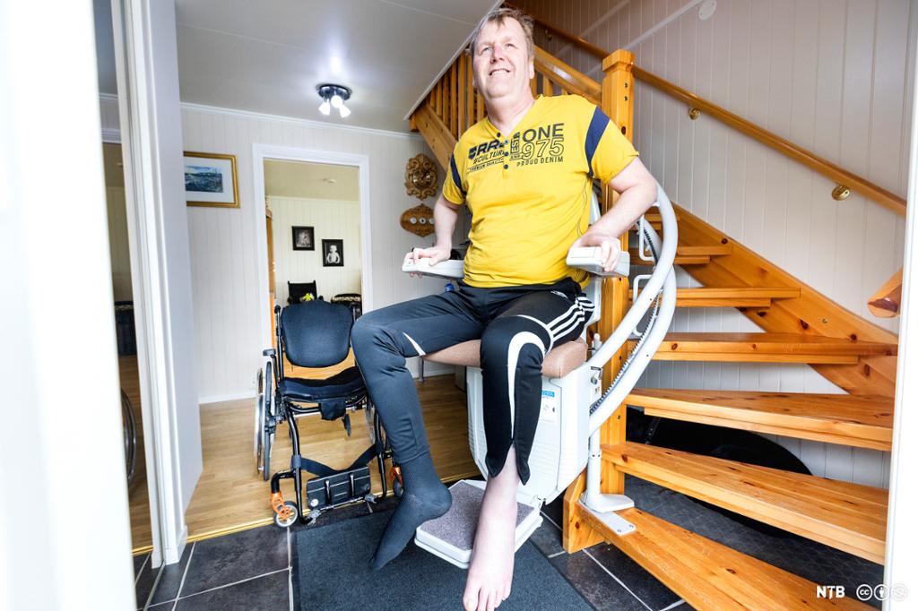 Mannlig rullestolbruker som har forflyttet seg til trappeheis. Foto. 